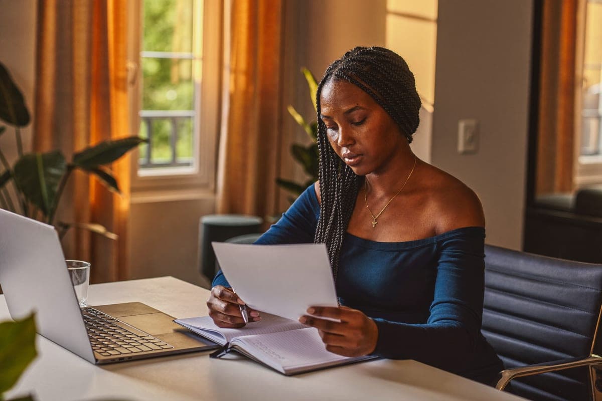 Une personne rédige sa lettre de motivation à son bureau.